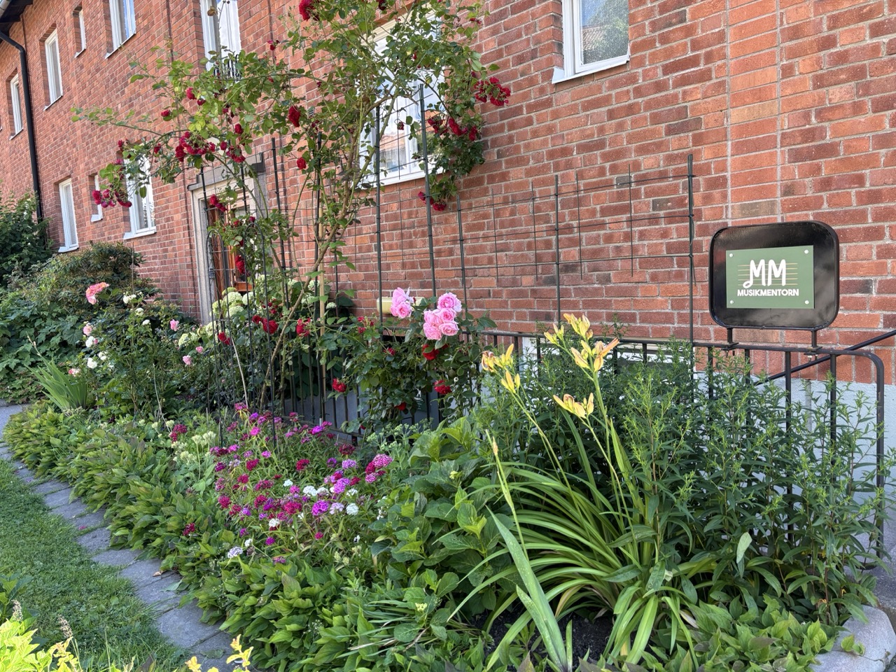 MusikMentorns skylt utanför deras studio i Stockholm med blommor omkring